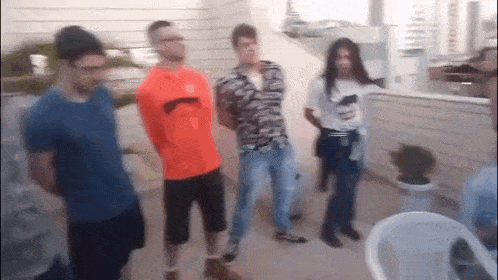 a group of people are standing next to each other on a balcony with their hands behind their backs .