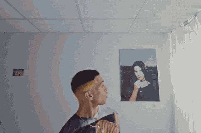 a man looks up at a painting of a woman on a wall