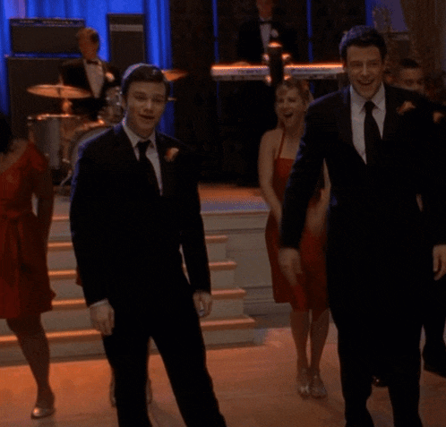 a man in a suit and tie is dancing with a group of women in red dresses
