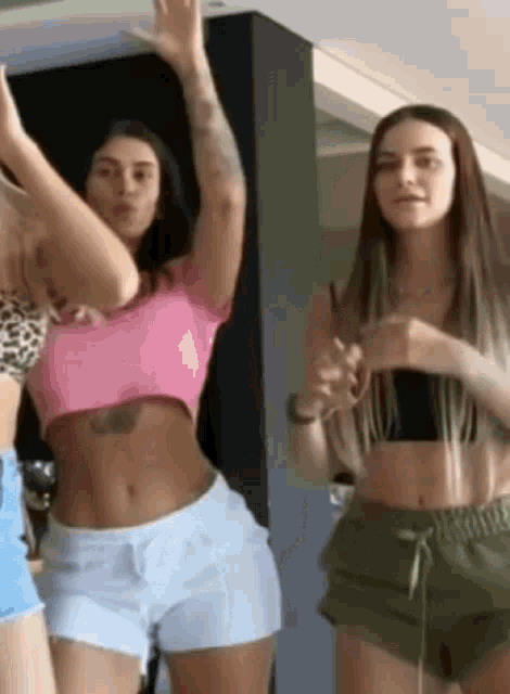 a group of women are standing next to each other and dancing in a room .