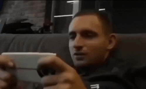 a man sitting on a couch looking at a cell phone