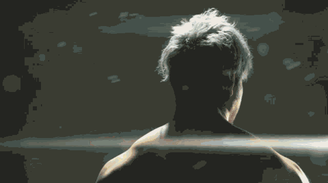 a shirtless man with his arms crossed stands in front of a field