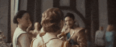 a group of people are standing in a room and one woman is holding a bottle