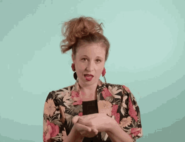 a woman wearing a floral jacket and earrings is making a face