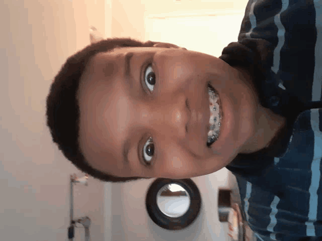 a young boy with braces on his teeth looks at the camera