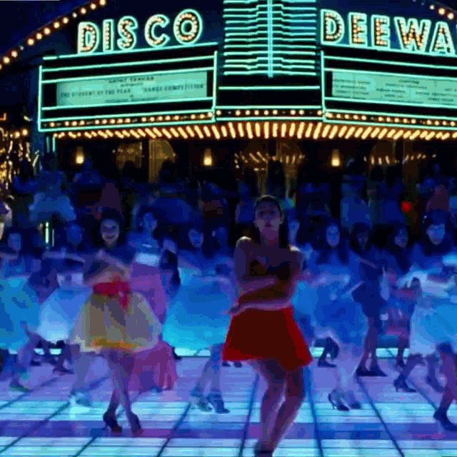 people are dancing in front of a disco deewa sign
