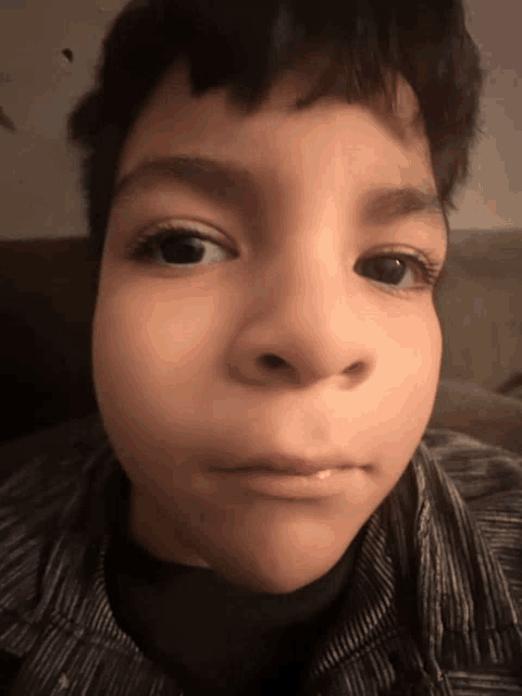 a close up of a young boy 's face with a striped shirt on