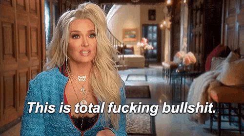 a blonde woman in a blue jacket is standing in a living room and says `` this is total fucking bullshit '' .