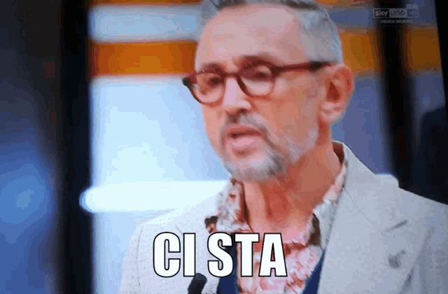 a man with glasses and a beard says ci sta in front of a microphone