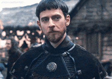 a man with a beard is wearing a black cape with a badge on it