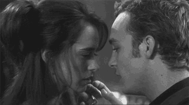 a man and a woman are kissing each other in a black and white photo .