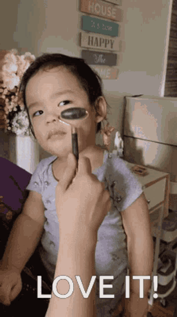 a little girl is getting a massage with a jade roller on her face and the words love it are below her