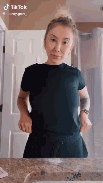 a woman is standing in front of a bathroom mirror wearing a black shirt .