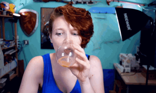 a woman is drinking from a glass in front of a megwer light