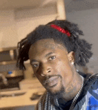 a man with dreadlocks and a beard is standing in a kitchen .