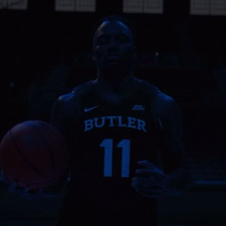 a man in a butler jersey is holding an orange basketball