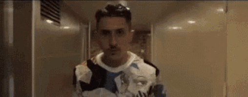 a young man with a mustache is standing in a locker room .