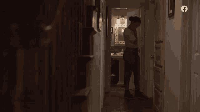 a woman standing in a hallway with a facebook logo on the bottom right