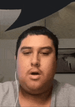 a man wearing headphones is making a funny face while looking at the camera .