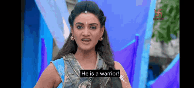 a woman in a warrior costume is standing in front of a blue and purple background .