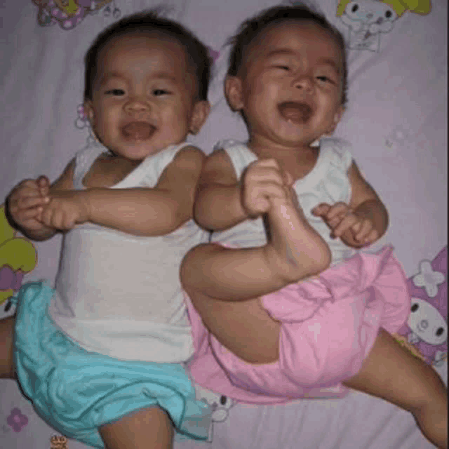 two babies are laying next to each other on a bed and one of them is crying