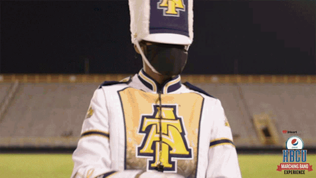 a marching band member wearing a mask and a hat with the letter a on it