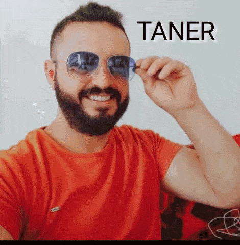 a man with a beard wearing sunglasses and a red shirt with the word taner written above him