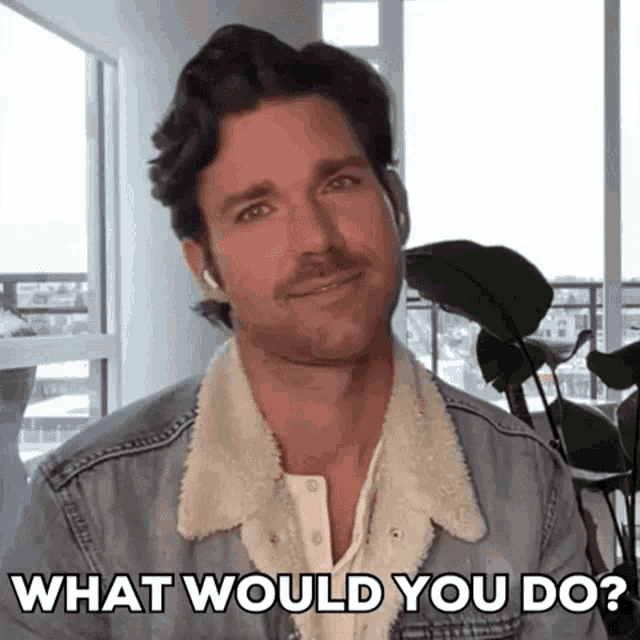 a man in a denim jacket is smiling and asking what would you do ?