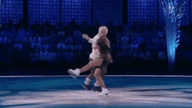 a man is carrying a woman on his shoulders while ice skating on a stage .