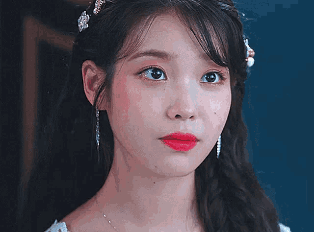 a close up of a woman 's face wearing a white dress and red lipstick .