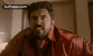 a man in a red shirt is making a funny face in a room .
