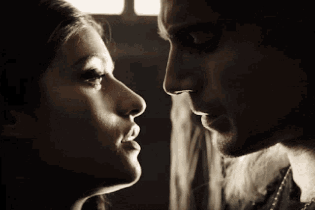 a man and a woman are looking at each other in a dark room
