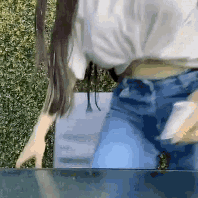 a woman in a white crop top and blue jeans is standing next to a table .