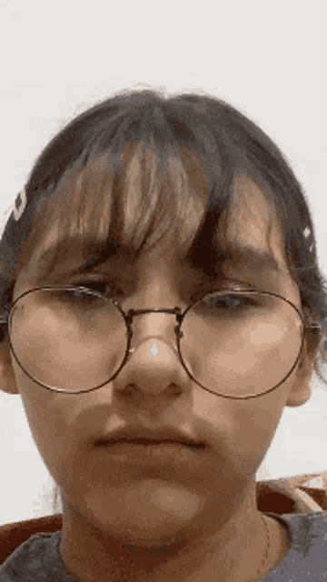 a close up of a girl wearing glasses making a face