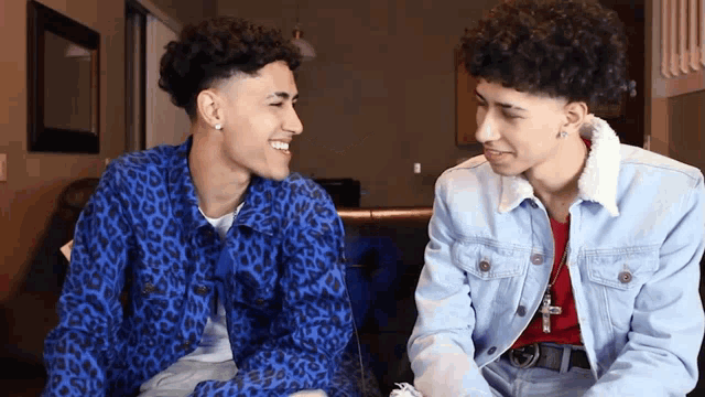 two young men are sitting next to each other on a couch .