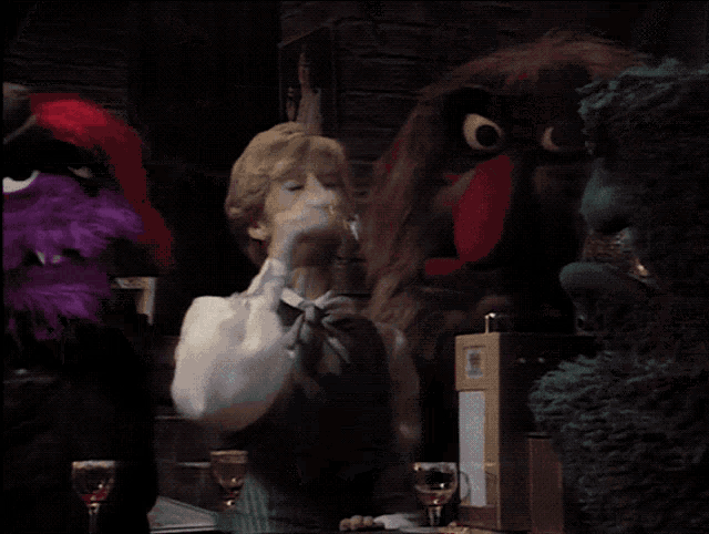 a man in a suit and tie stands in front of a puppet with big eyes