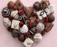a heart made out of chocolates on a pink surface .