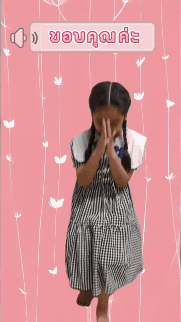 a girl in a plaid dress is standing in front of a pink background with flowers