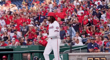 a baseball player wearing a washington nationals jersey is walking towards the dugout .