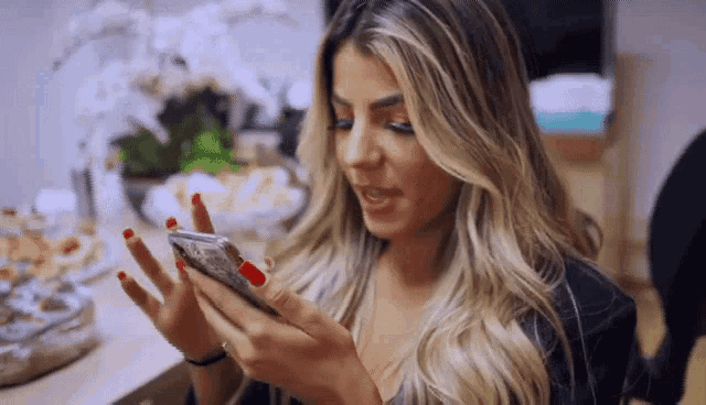 a woman with red nail polish is looking at her cell phone