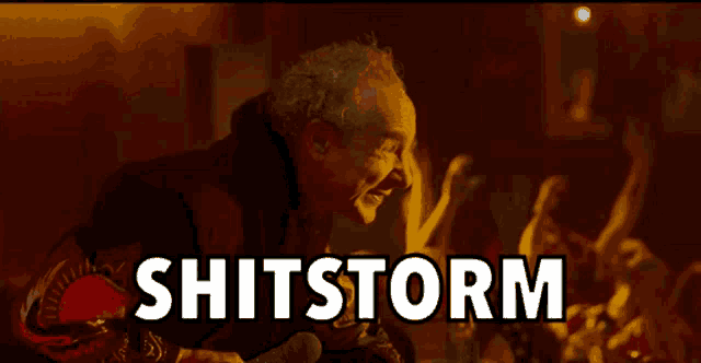 a man is screaming in front of a crowd with the word shitstorm above him