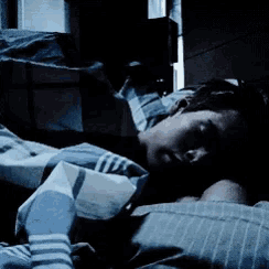 a person is sleeping in a bed with a blue striped blanket