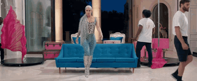 a woman in a leopard print jumpsuit is standing next to a blue couch