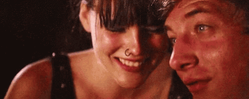 a man and a woman are looking at each other and smiling . the woman has a nose ring on her nose .