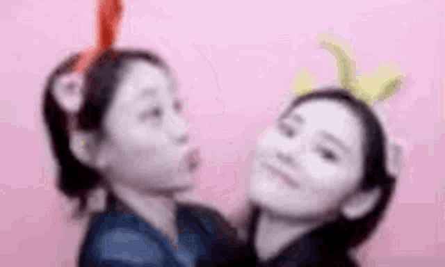 two girls wearing headbands with bunny ears are standing next to each other .