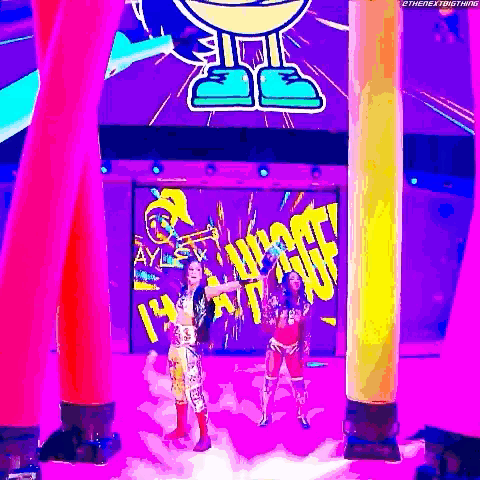 a couple of women are standing on a stage in front of a large screen .