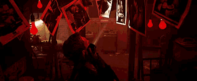 a man is talking on a cell phone in a dark room surrounded by pictures hanging on the wall .