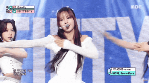 a girl in a white dress is dancing on a stage with a sign that says gravity