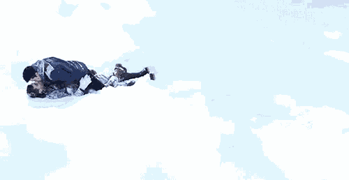 a man is pushing a child down a snow covered hill .