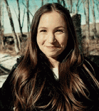 a woman with long brown hair is smiling and wearing a black coat .